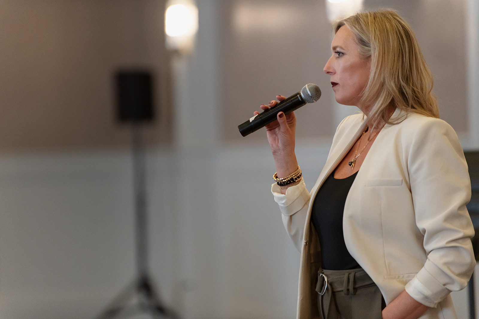 Carrie speaking to a room, microphone in hand