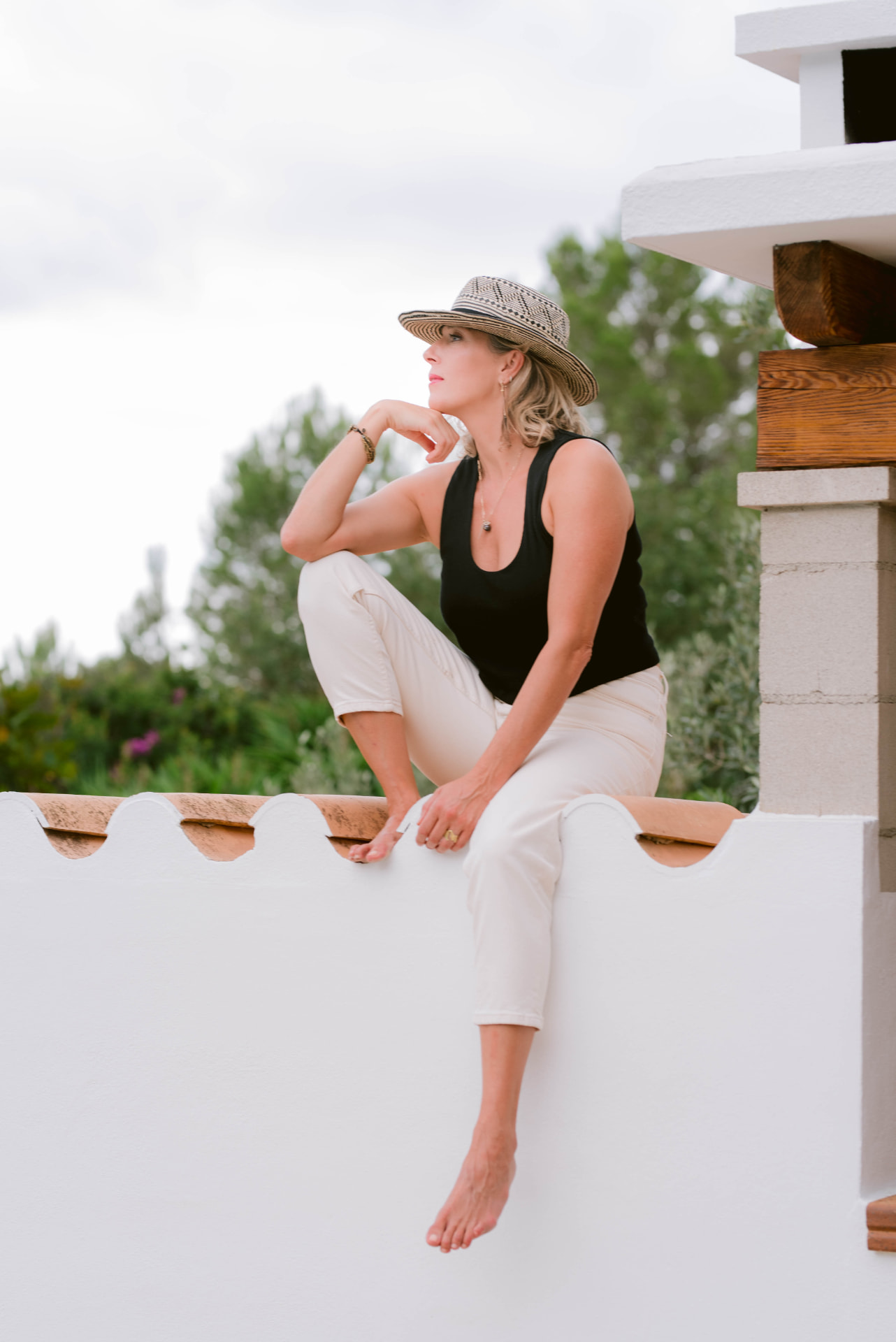 Carrie seated on a white wall in Ibiza, looking out